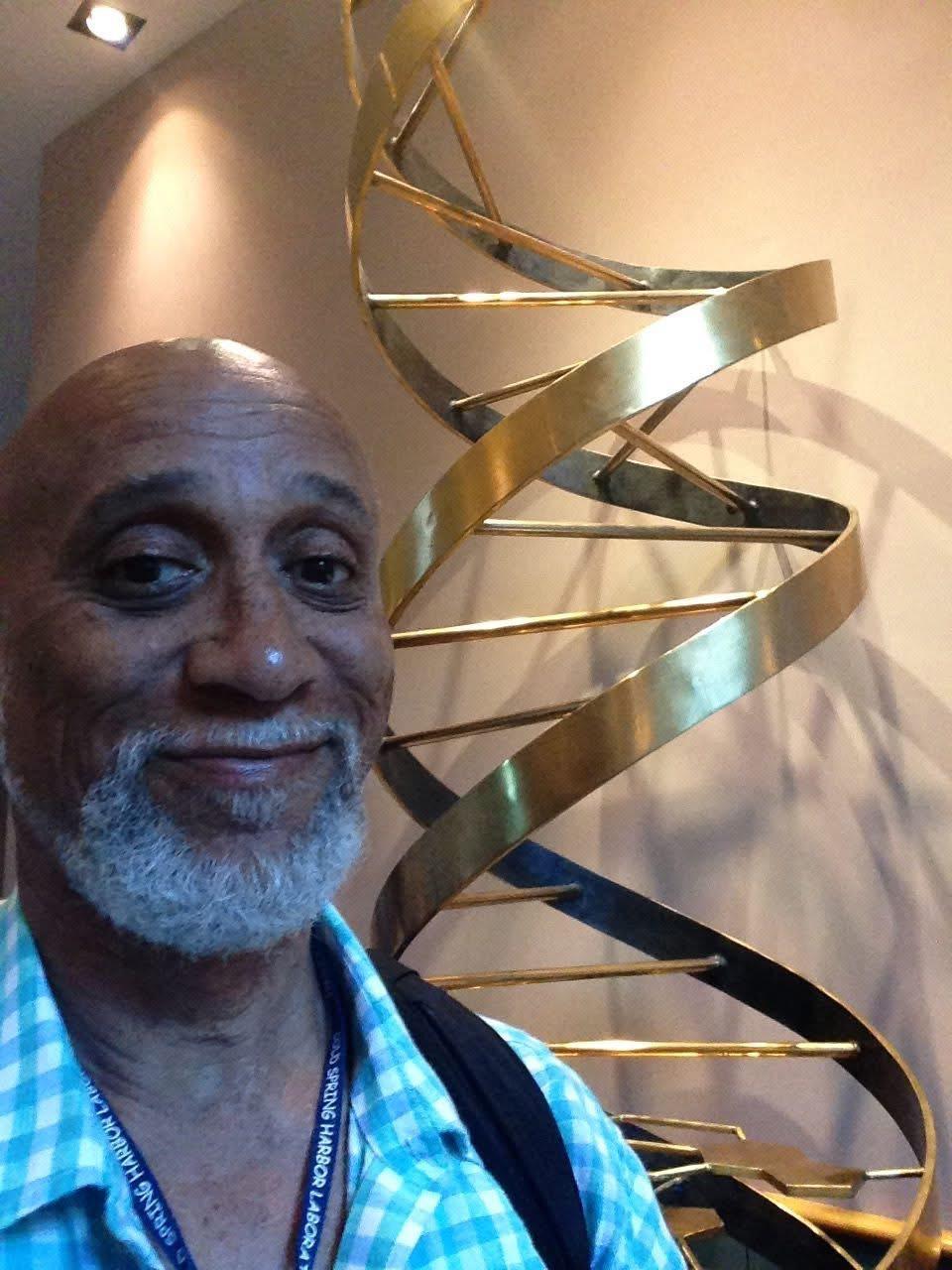 Dr. Frederick Tyson beside a DNA double-helix sculpture