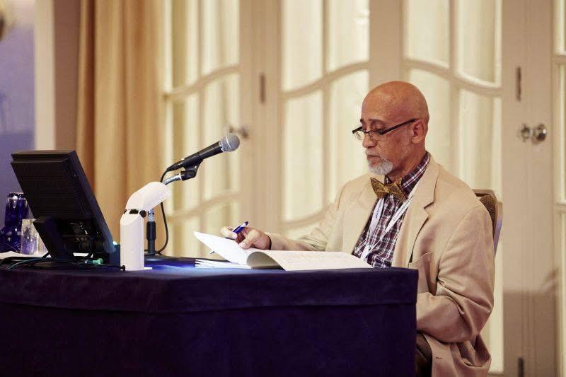Dr. Frederick Tyson reviewing notes at a seated panel microphone